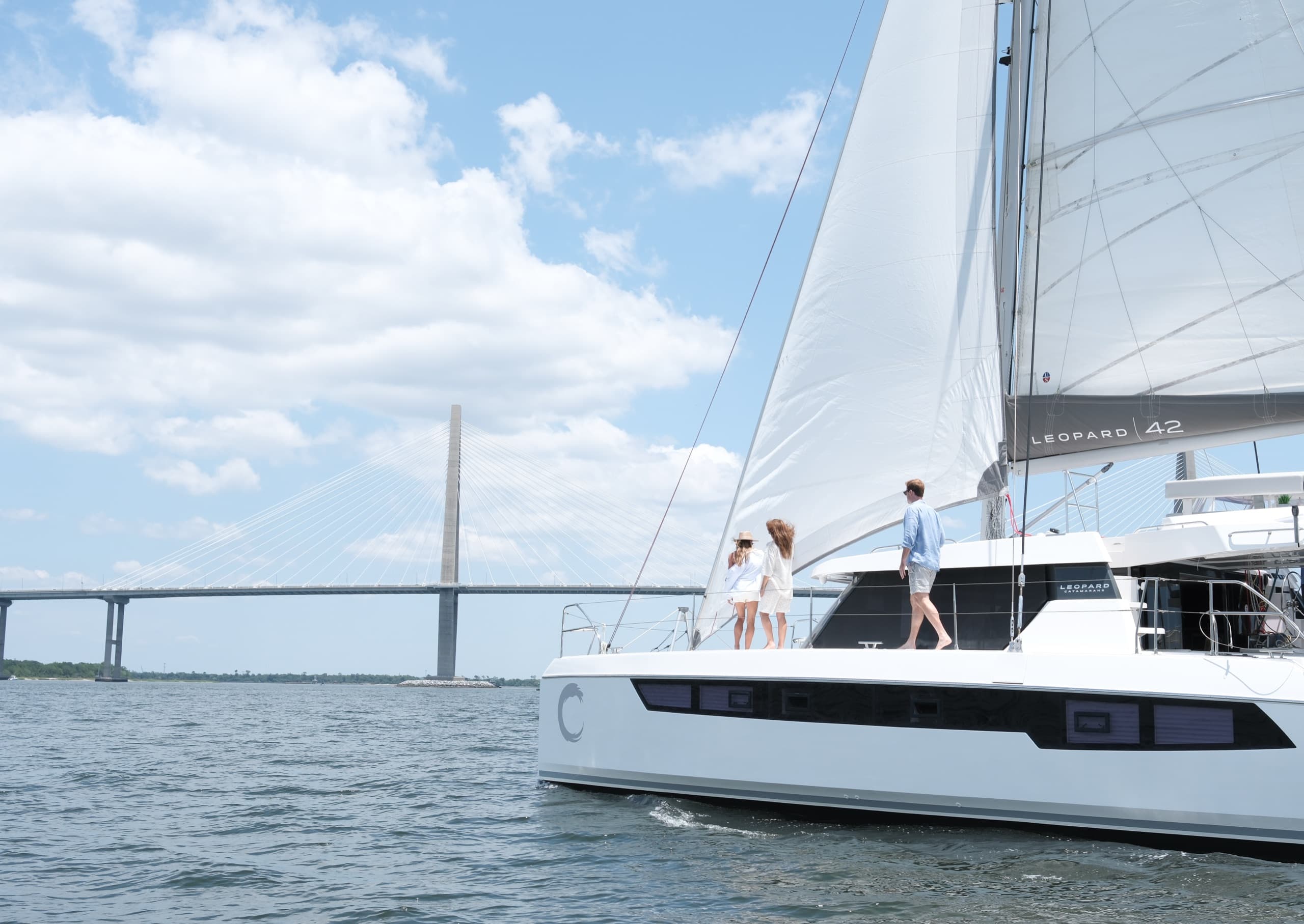 Charter guests walking towards the bow of Everything Zen at it sails towards the Arthur Ravenel Jr. Bridge, seen in the background.